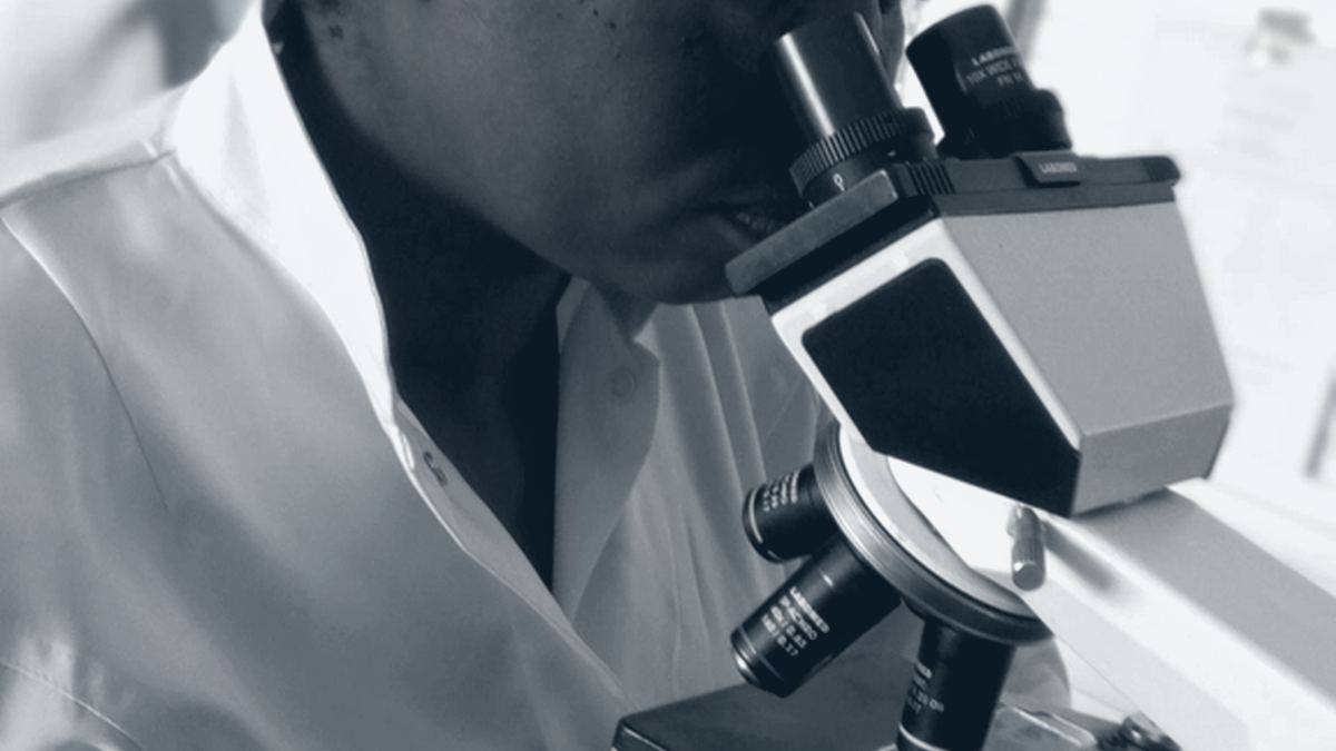Técnica de laboratorio revisando una muestra en el microscopio