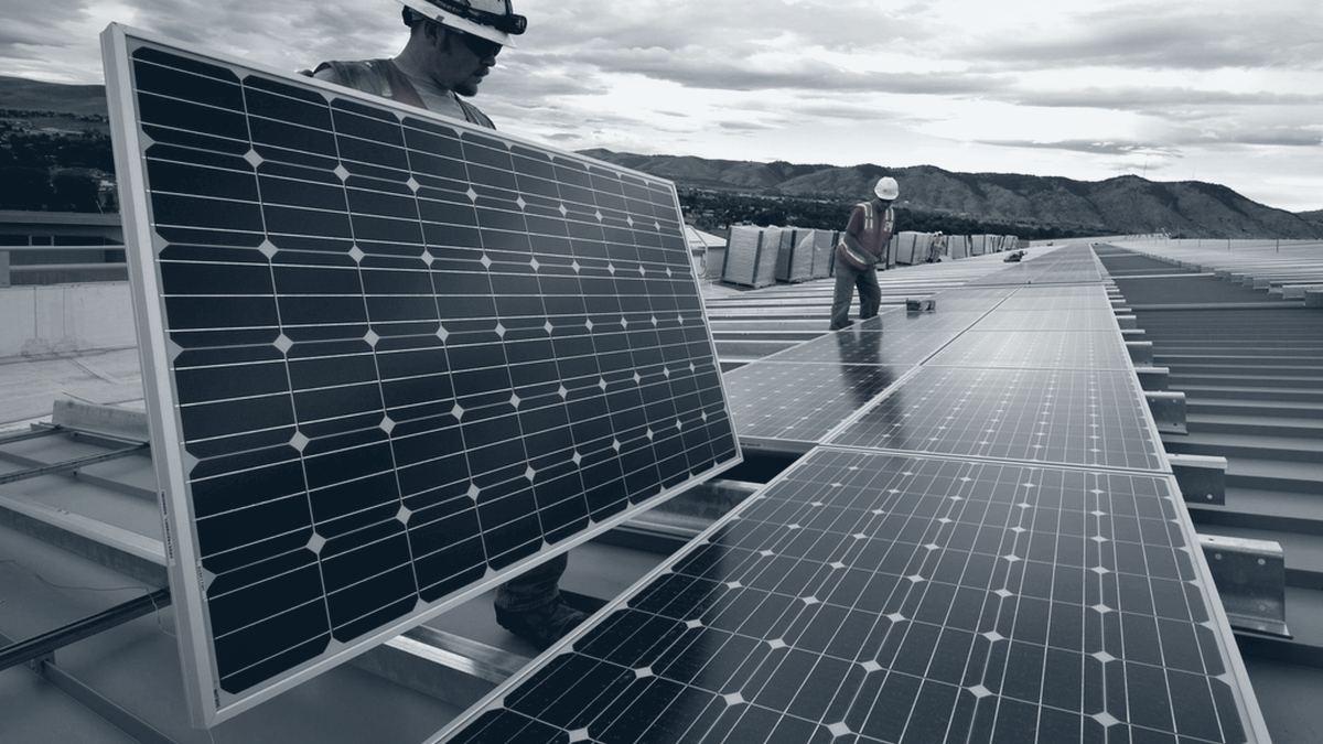 Instaladores colocando paneles solares sobre el techo de una nave